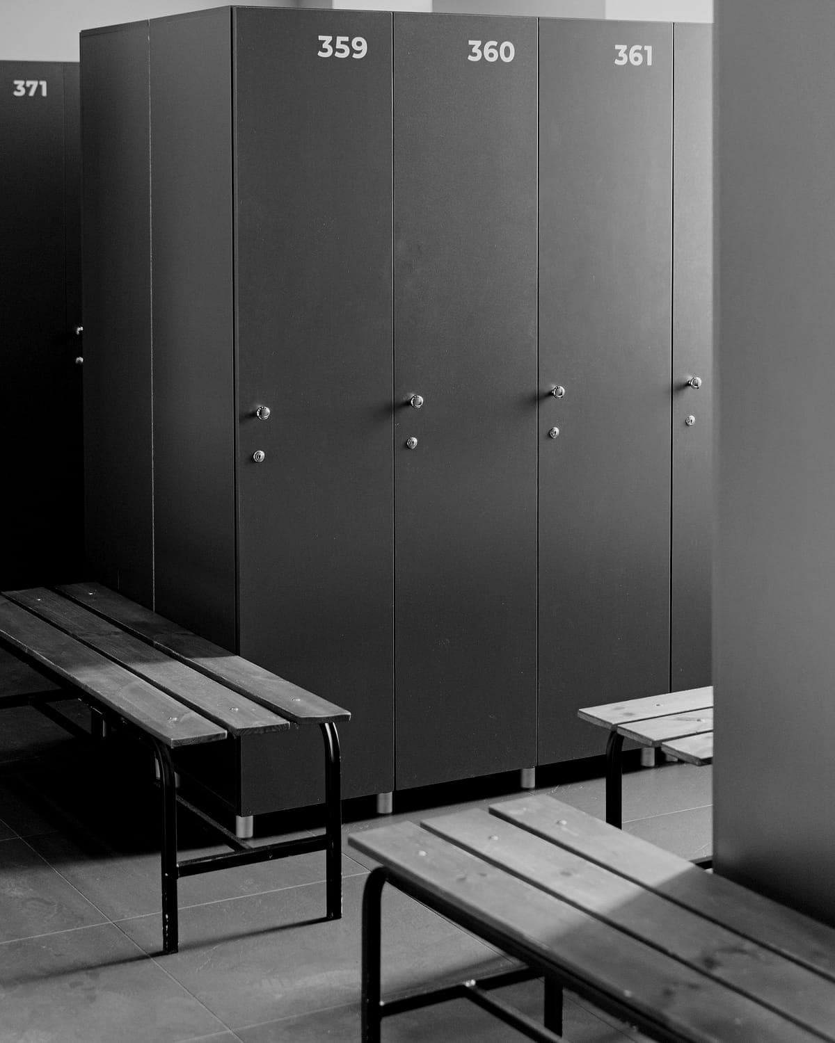 Numbered lockers and wooden benches in a quiet changing room.