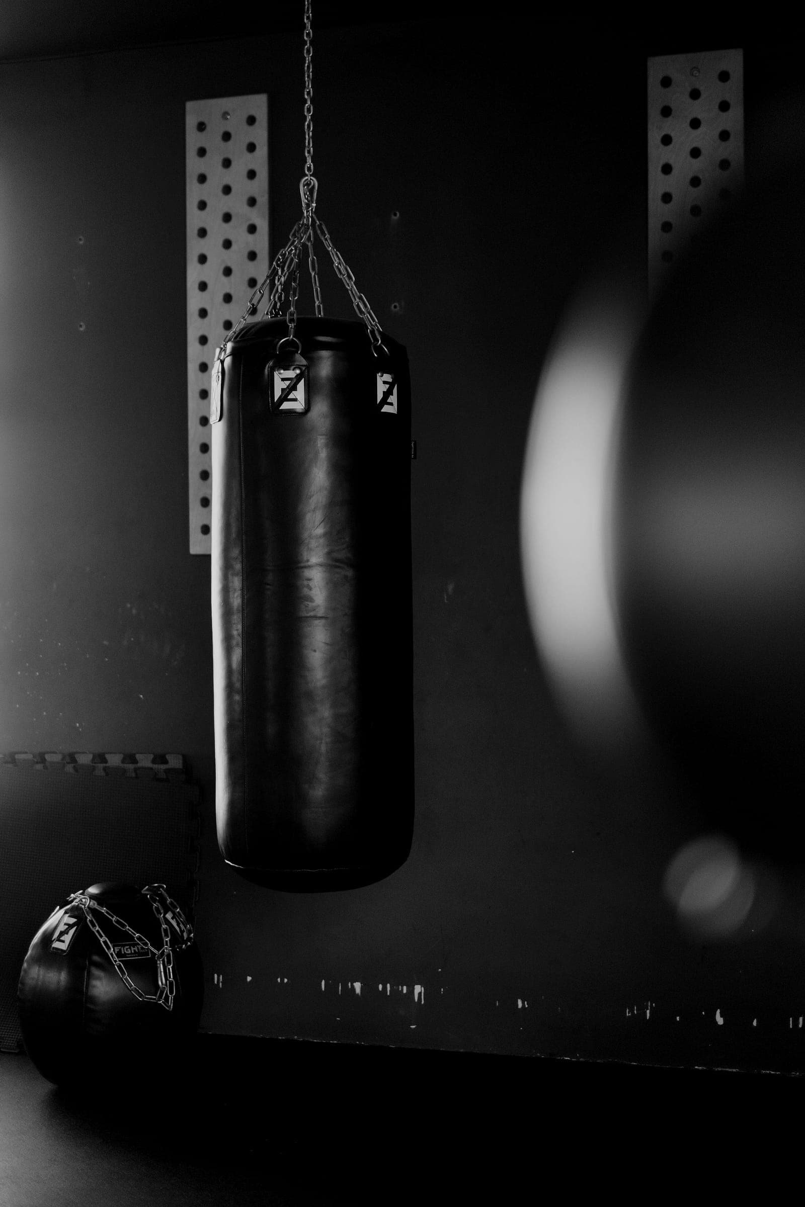 A heavy punch bag hangs against a dark wall.
